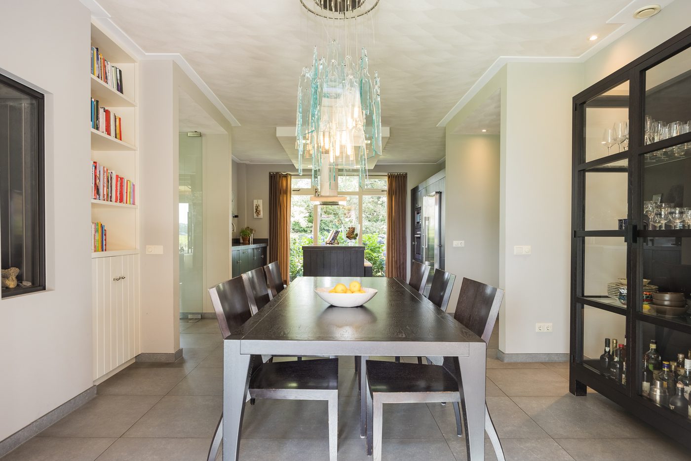 De eethoek met lange tafel, boekenkasten en vitrinekast