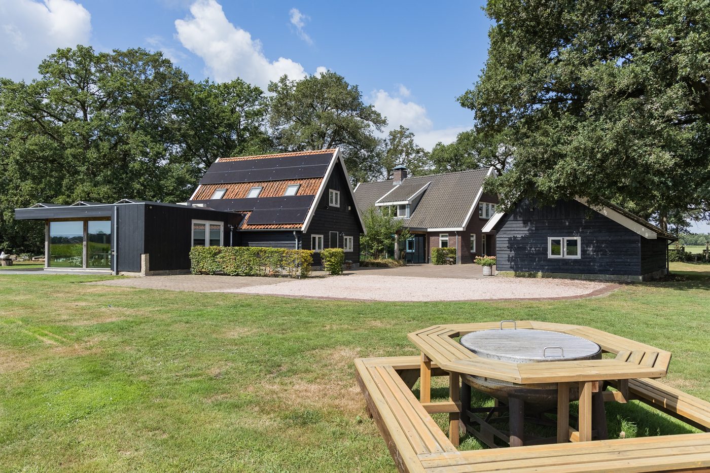 Zicht over het gazon op het kantoorgebouw, het landhuis en de kapschuur