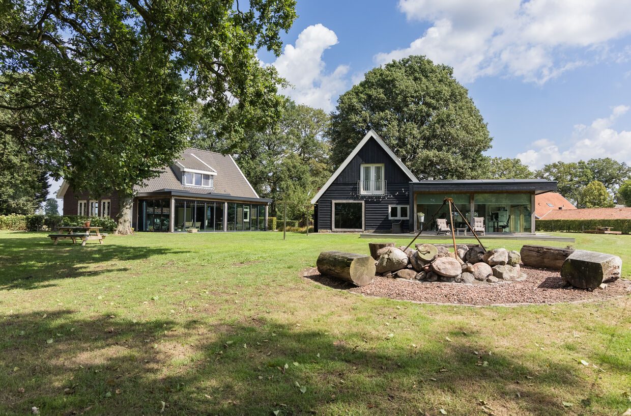 Het gazon met de vuurplaats en zicht op het kantoorgebouw en het landhuis