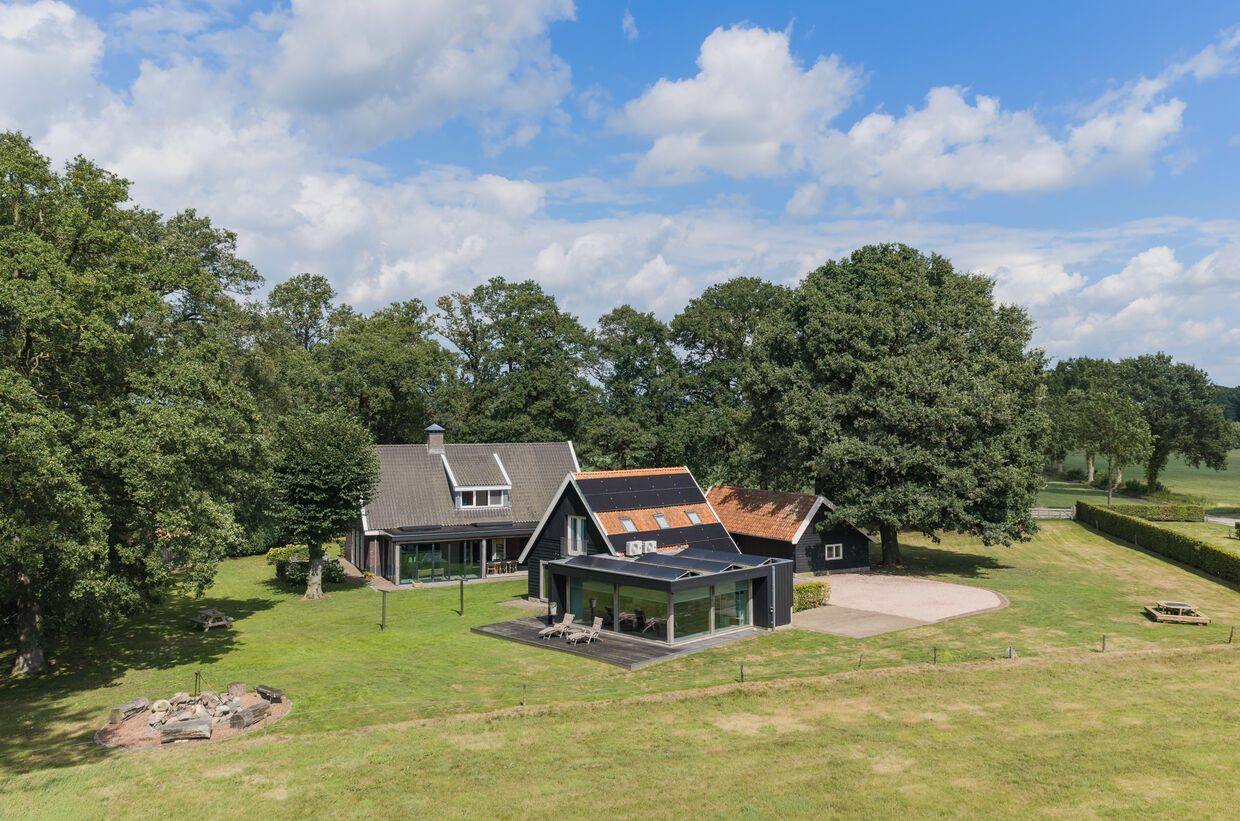 Het landhuis met serre en het vrijstaande kantoorgebouw op het ruime erf, tussen volwassen eikenbomen