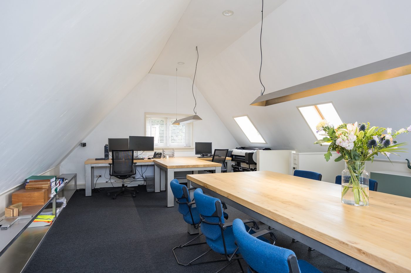 De verdieping van het kantoor met werkplekken en vergadertafel onder de kap