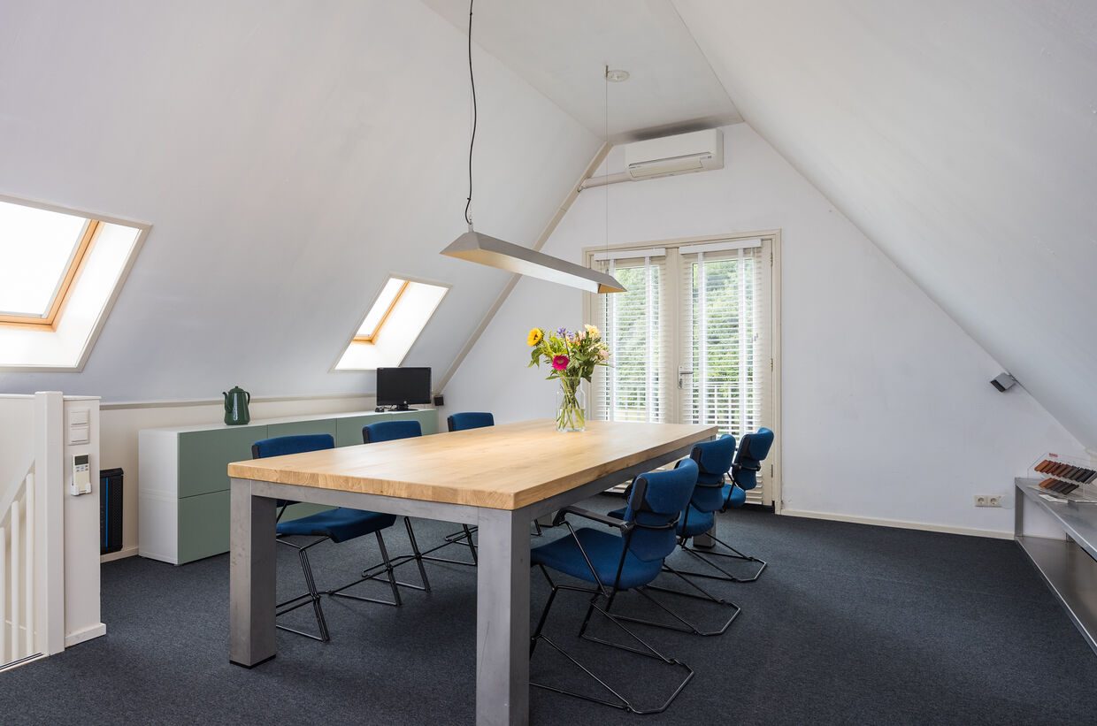 De multifunctionele verdieping met vergadertafel en Velux-dakramen