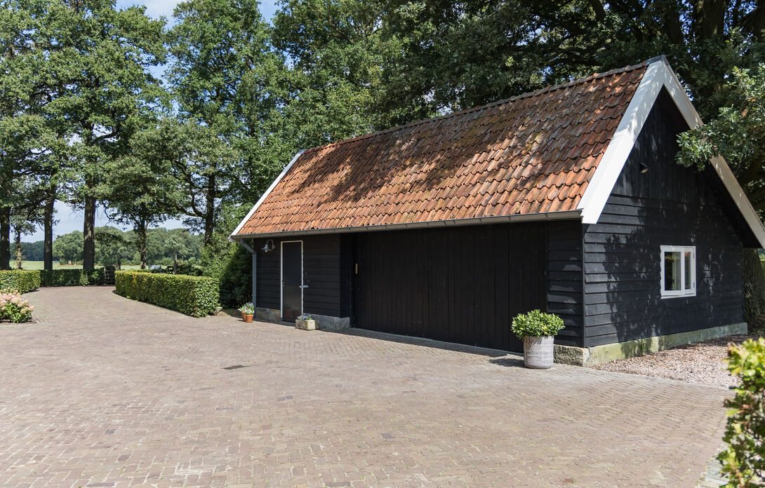 De kapschuur met pannendak en zwarte houten gevels, aan het klinkerplein