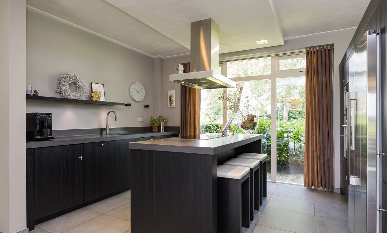 De leefkeuken met kookeiland en doorkijk naar de serre