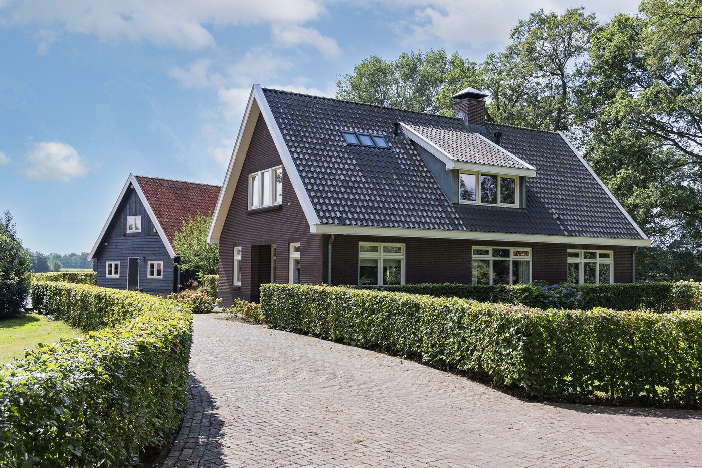 Het landhuis aan de oprit van gebakken klinkers, met hagen langs beide zijden
