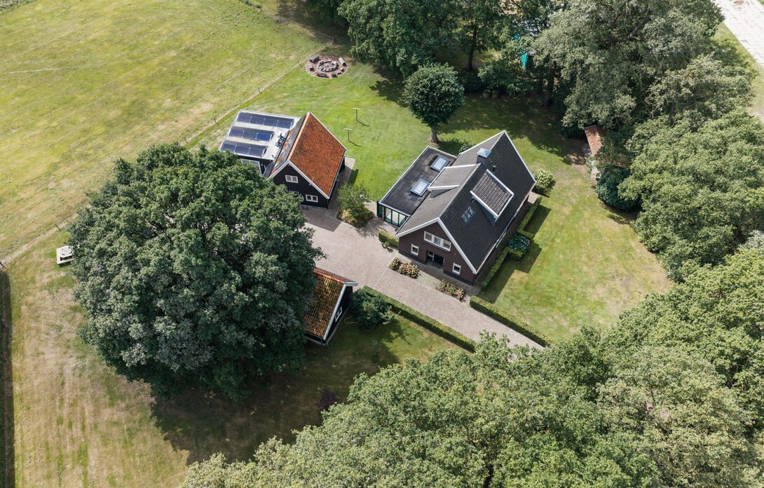 Luchtfoto van het erf: het landhuis, het kantoorgebouw en de kapschuren tussen de eikenbomen
