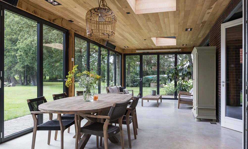 De eettafel in de serre met zicht op de tuin