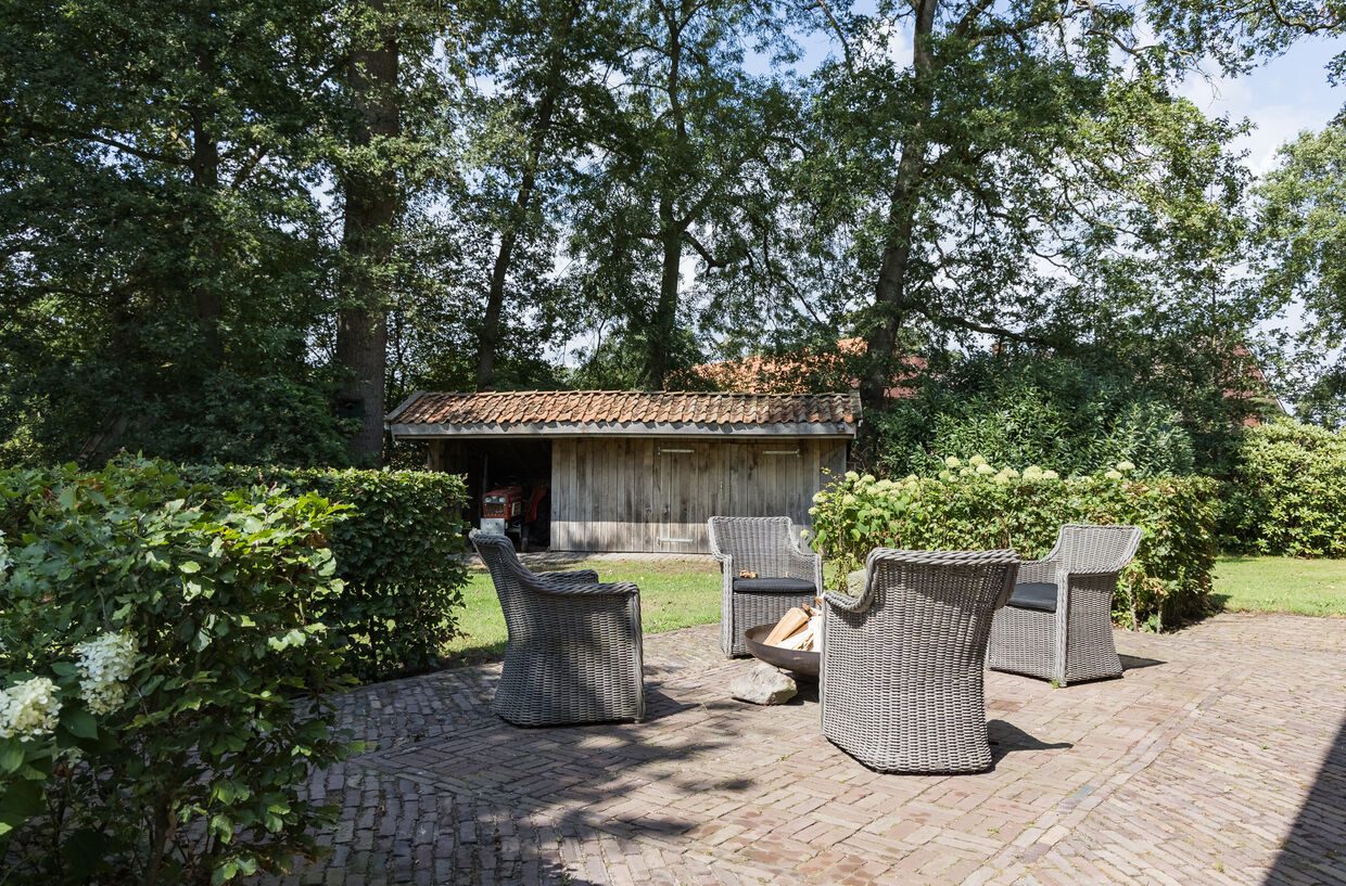 Zitplek op het terras bij de schuur, onder de eikenbomen