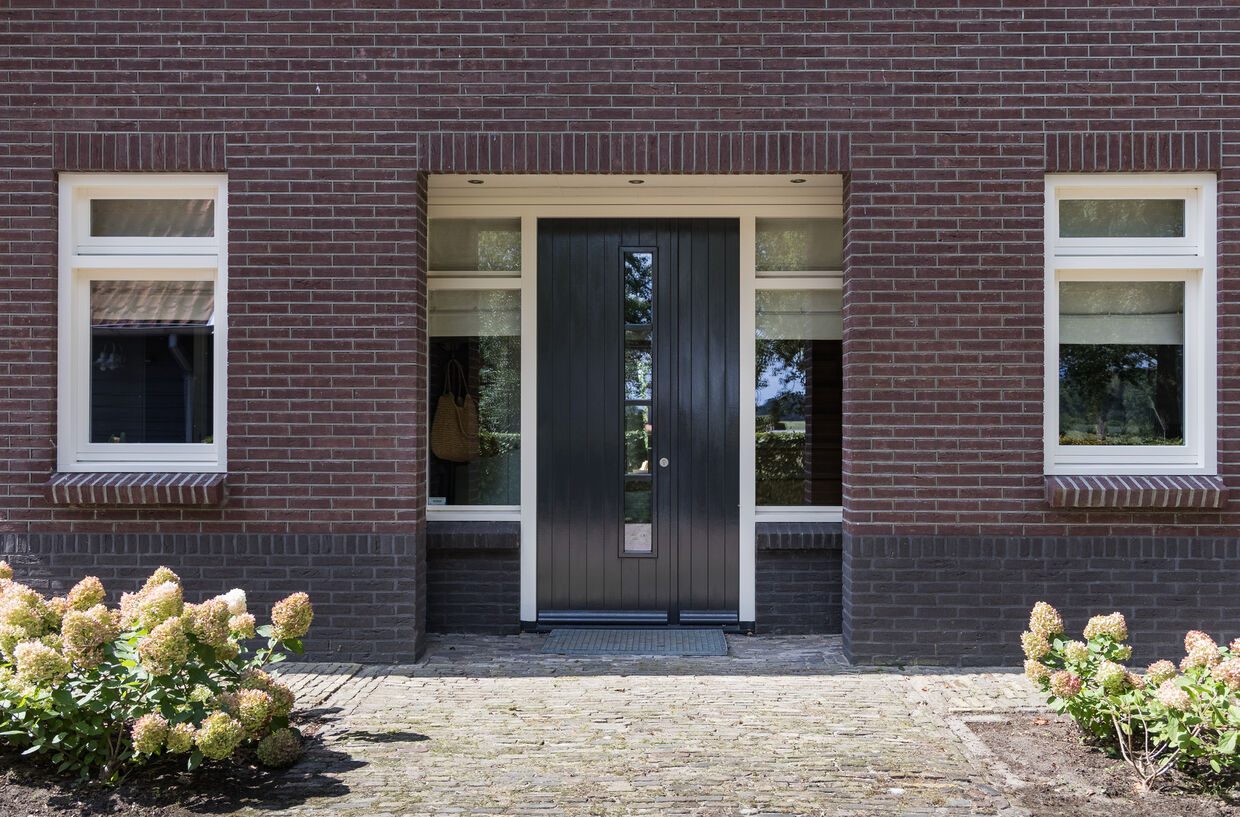 De voordeur van het landhuis met hortensia's in de border